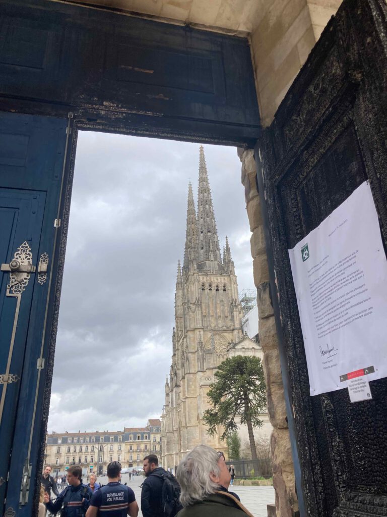 Blick auf die Kathedrale St. André de Bordeaux durch das durch einen Brandanschlag geschwärzte Tor der Rathauses